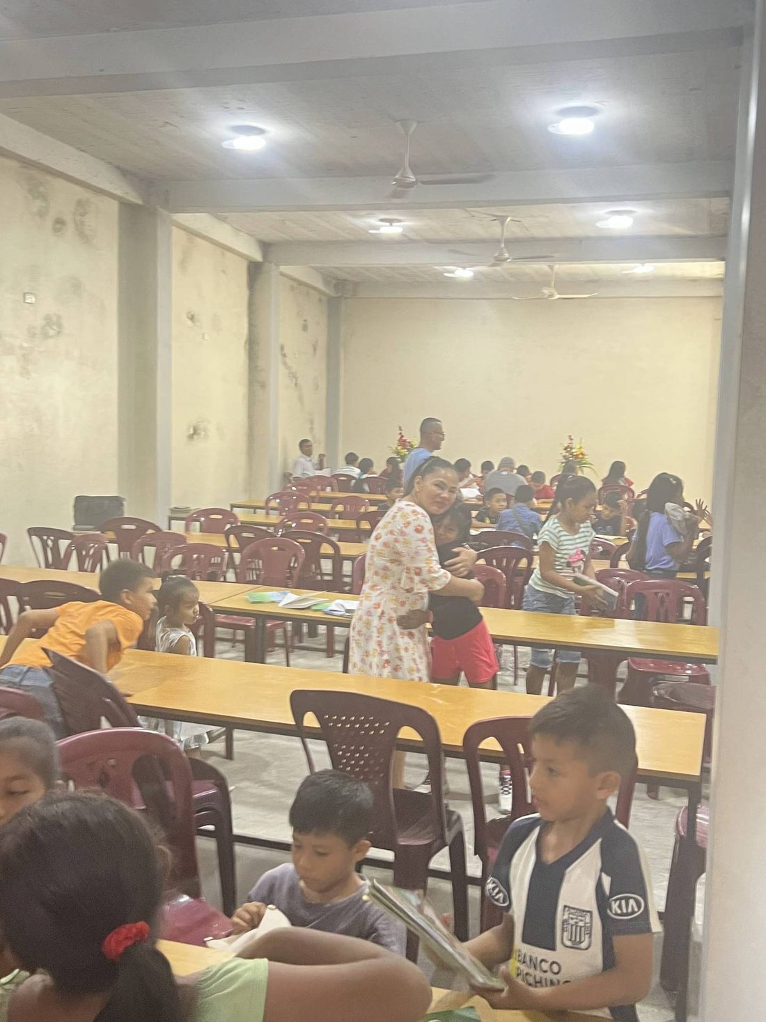Children gathered at tables inside a community hall