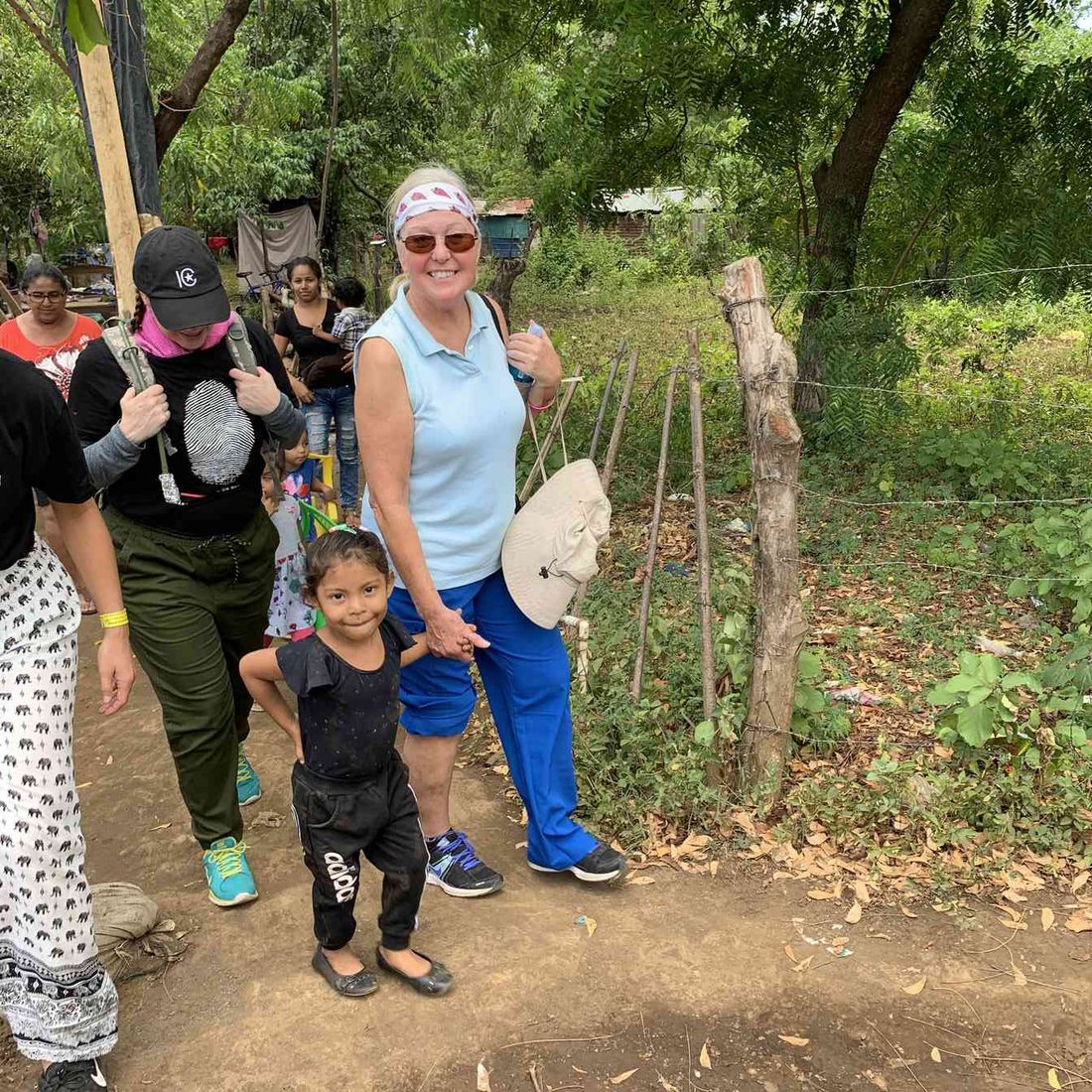 A team member walking a village path hand in hand with a child